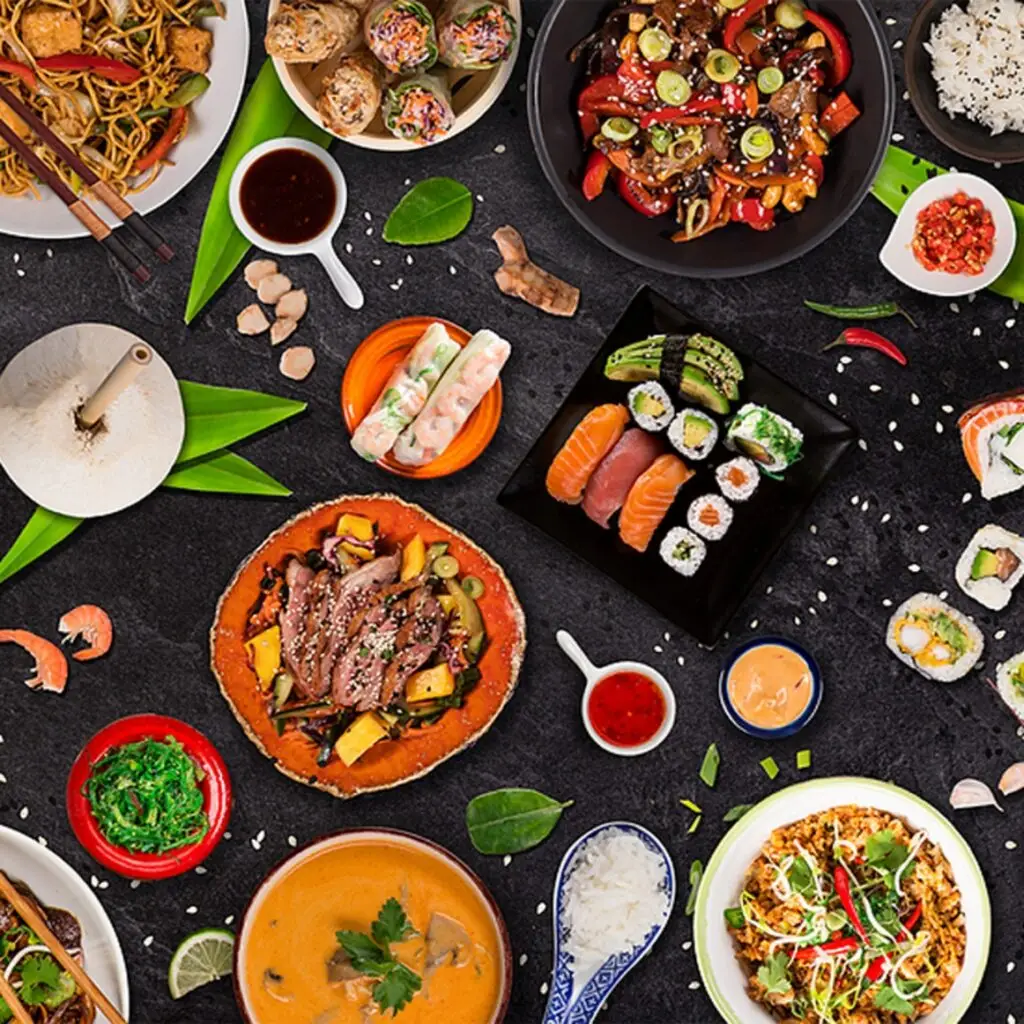 Top view of a vibrant spread of Asian dishes like noodles, sushi, curry, and spring rolls, styled for food and wine pairing.